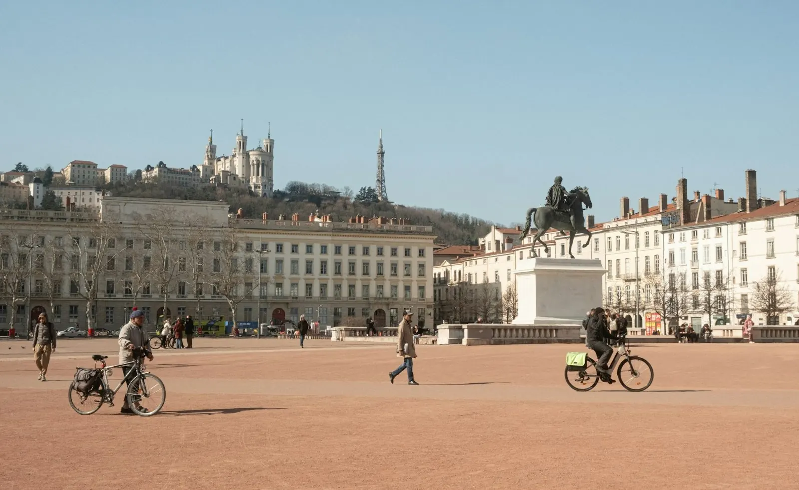 Cyclistes sur la place Bellecour à Lyon, la colline de Fourvière au fond