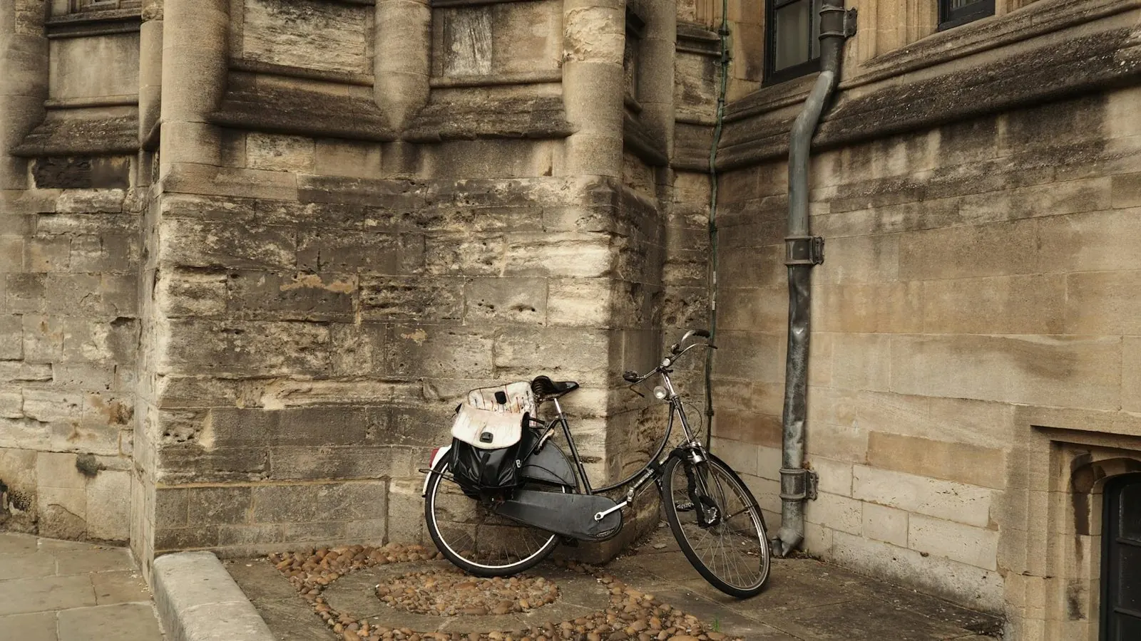 Vélo noir garé contre un mur de pierre